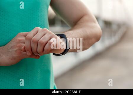 Portrait der kaukasischen Kerl in Azure t-shirt Fitness tracker Lesungen vor oder nach dem Joggen. Stockfoto