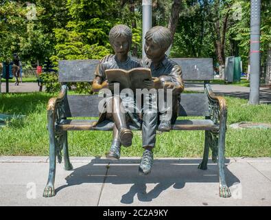 Bukarest/Rumänien - 05.30.2020: Bronzestatue eines Mädchens und eines Jungen, der ein Buch auf einer Bank liest. Stockfoto