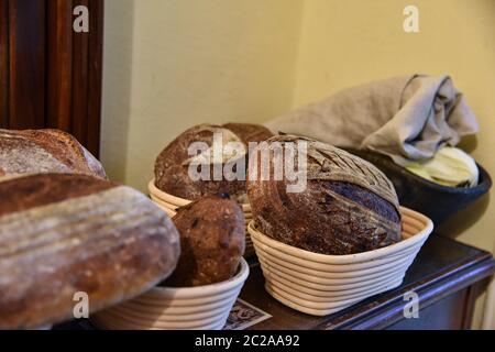 Ein frischer knuspriger Laib hausgemachtes Brot. Hausgemachte rustikale sauer. Braunes Brot. Verschiedene Arten von Broten. Brotscheiben. Atmosphärenbild einer Küche im Landhausstil. Stockfoto