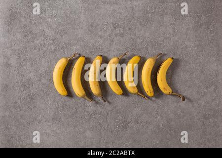 Reife Bananen auf grauem Betongrund. Foto innen. Fotokunst. Draufsicht Stockfoto