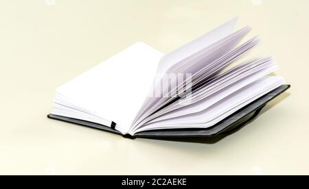 Öffnen Sie das Hardcover-Notizbuch auf einem weißen Tisch. Stockfoto