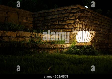 Eine alte Gartenlaterne leuchtet in der Nacht. Selektiver Fokus Stockfoto