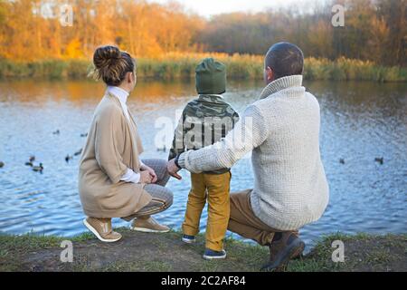 Vater, Mutter und kleiner Sohn füttern Enten Stockfoto