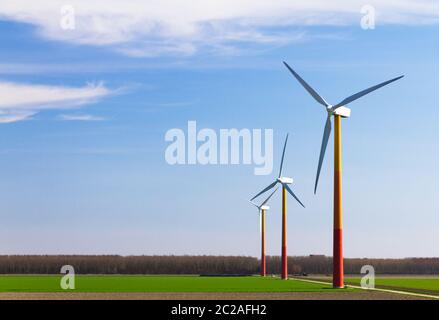 Schöne Landschaft mit mehreren modernen Windmühlen Turbinen für grüne nachhaltige Energie in einem Feld in den Niederlanden mit einem blauen Himmel Stockfoto