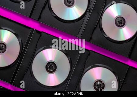 Die Entwicklung digitaler Medien. SD Blu-ray Discs in offenen schwarzen Boxen auf violettem Hintergrund. Blick von oben. Kreativer Hintergrund Stockfoto