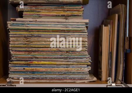 Ein Stapel schäbiger alter Zeitschriften und Comics auf einem Schrankregal. Sammlung von zufälligen Zeitschriften. Sammeln, Hobbys. Seitenansicht. Selektiver Fokus. Stockfoto