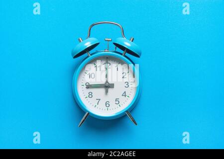 Blauer Vintage-Wecker bei neun Uhr auf blauem Hintergrund mit Platz für Kopien aus einem hohen Winkel Stockfoto