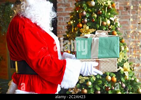 Der Weihnachtsmann stellt heimlich Geschenkschachteln am Weihnachtsbaum Stockfoto