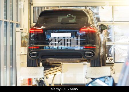 Auto auf einem Rad-Justierung Lift im Auto-Service in einer modernen Garage. Diagnose des Fahrgestells des Fahrzeugs, das am Aufzug angehoben wurde Stockfoto
