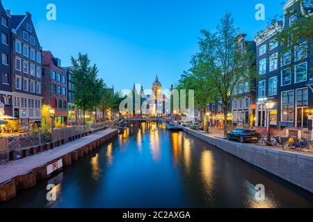 St. Nikolaus Kirche mit Amsterdam Skyline bei Nacht in den Niederlanden Stockfoto