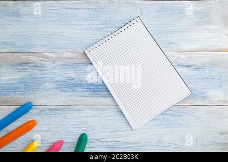 Schulkinderkonzept. Buntstifte oder Buntstifte und Notizblock auf einem blau-weißen, verschneiten Vintage-Holzhintergrund. Das Vie Stockfoto