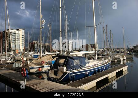 Marina und die umliegenden Gebäude in Ipswich, Suffolk, Vereinigtes Königreich mit sehr dunklen Gewitterwolken und Sonnenlicht beleuchtet die Boote und Bu Stockfoto