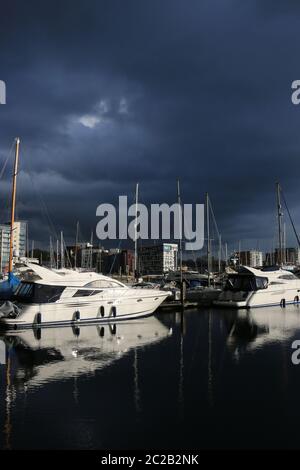 Marina und die umliegenden Gebäude in Ipswich, Suffolk, Vereinigtes Königreich mit sehr dunklen Gewitterwolken und Sonnenlicht beleuchtet die Boote und Bu Stockfoto