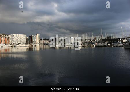 Marina und die umliegenden Gebäude in Ipswich, Suffolk, Vereinigtes Königreich mit sehr dunklen Gewitterwolken und Sonnenlicht beleuchtet die Boote und Bu Stockfoto