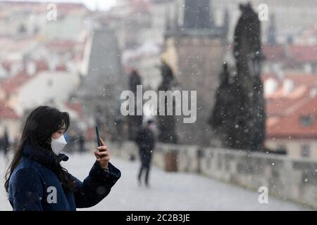 Prag, Tschechische Republik. März 2020. Eine Touristen mit Gesichtsmaske macht am 22. März 2020 ein Foto mit ihrem Handy auf der Karlsbrücke in Prag, Tschechien. Seit März 25 dürfen Menschen nur paarweise im öffentlichen Raum auftreten, so das vom tschechischen Gesundheitsministerium erlassene Dekret. Familien machen Ausnahme. Kredit: Ondrej Deml/CTK Foto/Alamy Live Nachrichten Stockfoto