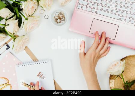 Stylische Flatlay-Rahmenanordnung mit pinkem Laptop, Rosen und anderen Accessoires auf Weiß. Feminine Business-Mockup, Copyspace Stockfoto