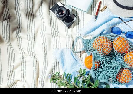 Feminine Sommer Picknick Flatlay, Früchte, Beeren und Filmkamera auf gestreiften Baumwolldecke Stockfoto