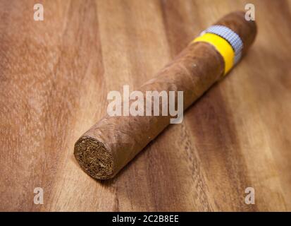 Gerollte Zigarre aus einem Tabakblatt auf einem hölzernen Hintergrund, kleine Schärfentiefe Stockfoto
