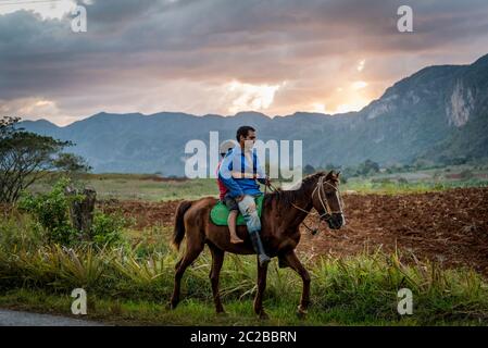 Vater und Sohn reiten bei Sonnenuntergang im Vinales Tal, Kuba Stockfoto