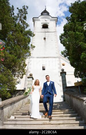 Der Kuss. Braut und Bräutigam halten die Hände, die Treppe hinunter vor einer kleinen lokalen Kirche zu gehen. Stilvolle Hochzeit Paar küssen. Stockfoto