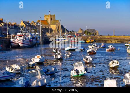 Hafen bei Ebbe am Ende des sonnigen Tages und Kirche Saint-Nicolas von Barfleur, eine Gemeinde auf der Halbinsel Cotentin in Frankreich Stockfoto