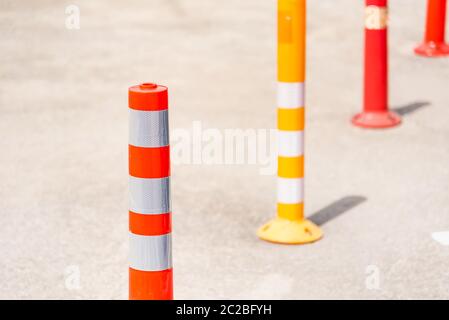 Leuchtend orange Verkehrskegel stehen in einer Reihe auf Asphaltstraße. Stockfoto