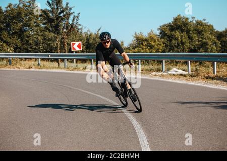 Reifer Mann mit athletischen Körper trägt Sportkleidung, Schutzhelm und Spiegelbrille Fahrrad schnell an frischer Luft fahren. Konzept der sportlichen Aktivität Stockfoto