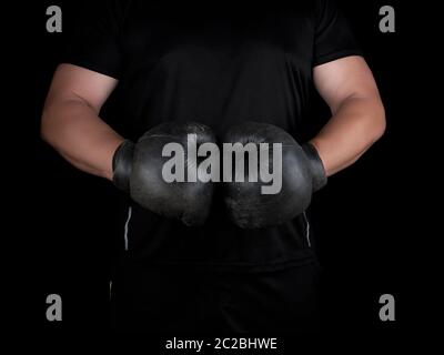 Mann steht in einem Rack, das Tragen von sehr alten Vintage Schwarze Boxhandschuhe auf seinen Händen, Low Key Stockfoto