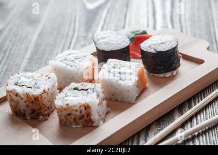 Drei verschiedene Arten von japanischen Rollen mit Wasabi und Ingwer auf Bambus tablett auf schönen hölzernen Hintergrund Stockfoto