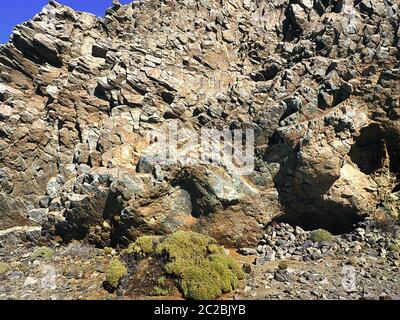 Eine hohe natürliche Lavasteinwand, bestehend aus bunten Quadersegmenten, die locker geschichtet sind, durch Wind und Wetter zerfallen. Außergewöhnliche Steinstruktur Stockfoto