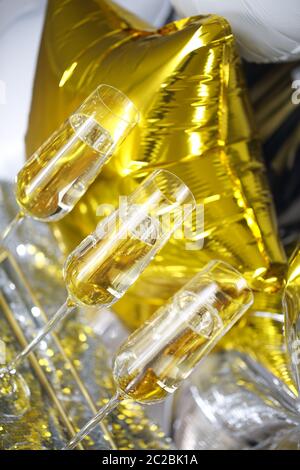 Nahaufnahme von glänzenden Gläsern Champagner über goldenen und silbernen Ballons Hintergrund Stockfoto