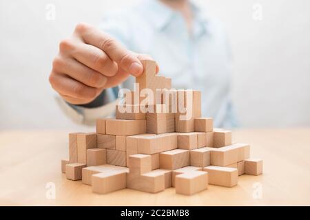 Des Menschen Hand stapeln Holz- Bausteine. Business Development Konzept Stockfoto