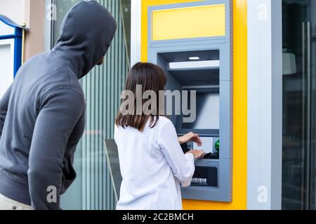 Männer versuchen, den PIN-Code zu Stehlen von der Frau mit ATM-Karte für Bargeldbezug Stockfoto