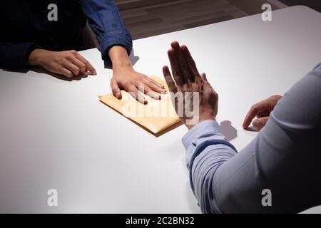 In der Nähe von einem Geschäftsmann Hand ablehnen, Schmiergeld Geschäftsfrau über den weißen Schreibtisch zu nehmen Stockfoto