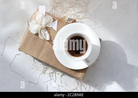 Weihnachtsdesign-Konzept. Weihnachtsgeschenk-Schachtel mit trockener Orchideenblume und einer Kaffeetasse auf Weiß. Weihnachts-Flatlay. Stockfoto