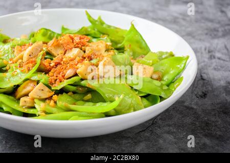 Rühren Sie die Schneeerbsen mit vietnamesischen gegrillten Schweinefleisch Wurst, Belag mit knusprig gebratenen Schalotten und Garl Stockfoto