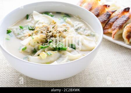 Wan-tan-Suppe mit Frühlingszwiebeln in einer weißen Schüssel serviert, selektiver Fokus Stockfoto