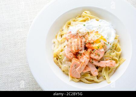 Fettucine mit Lachs, Ei und Parmesan, auf weiße Platte serviert. Stockfoto