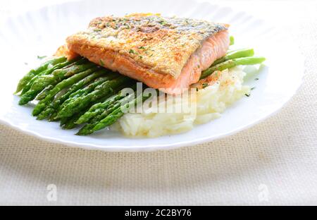 Gegrillter Lachs garniert mit Spargel und Kräutern und Kartoffelbrei, serviert auf weiß beschichtet. Stockfoto