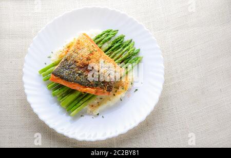 Gegrillter Lachs garniert mit Spargel und Kräutern und Kartoffelbrei, serviert auf weiß beschichtet. Stockfoto