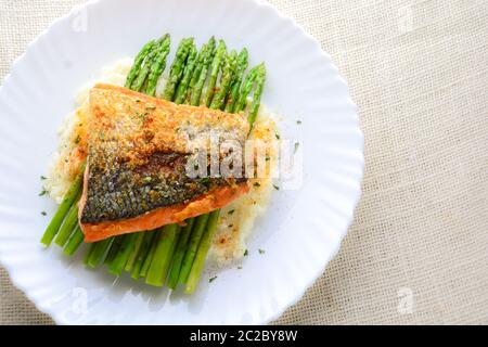 Gegrillter Lachs garniert mit Spargel und Kräutern und Kartoffelbrei, serviert auf weiß beschichtet. Stockfoto