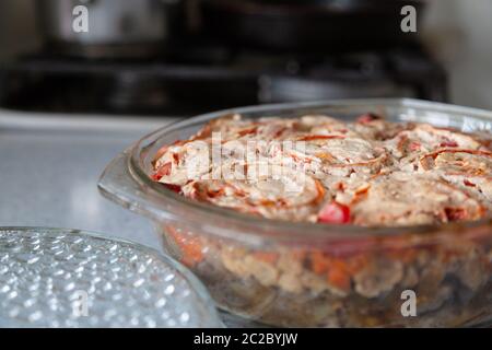 Gemüsegerichte aus verschiedenen Gemüsesorten, die in einer Glasschüssel gebacken werden. Gericht mit geschmorten Tomaten wird im Ofen gekocht. Gericht mit Gemüse auf dem Hintergrund der Stockfoto