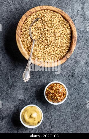 Gelber Senf und ganze Senf und senfkörnern am Küchentisch. Ansicht von oben. Stockfoto