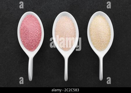 Rot, orange und Gelb instant Gelee oder Wackelpudding Pulver auf kleine Löffel, Overhead fotografiert auf Schiefer Stockfoto