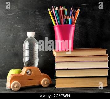 Stapel von Büchern und ein rosa Schreibwaren Glas mit bunten Bleistifte aus Holz, Holz- Auto, zurück in die Schule Konzept Stockfoto