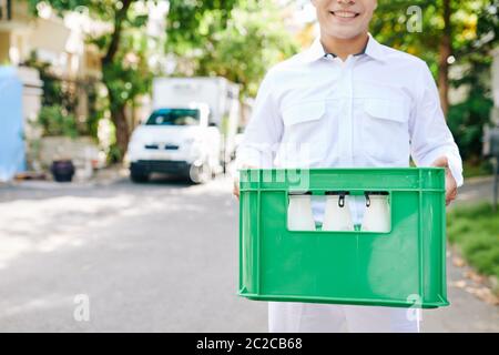 Horizontal Kopf abgeschnitten Aufnahme der Lieferung Mann trägt weiße einheitliche Kleidung im Freien stehend mit Milchflaschen, kopieren Raum Stockfoto