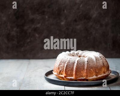 Weibliche Hand bestreuen Puderzucker auf Muffin Kuchen Stockfoto
