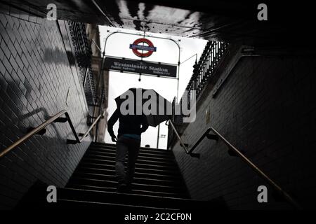 Ein Mann mit Regenschirm taucht aus der Westminster Underground Station in London auf, als heftige Gewitter über den Norden Englands und Schottlands fegten und stellenweise Blitzüberflutungen verursachten. Stockfoto