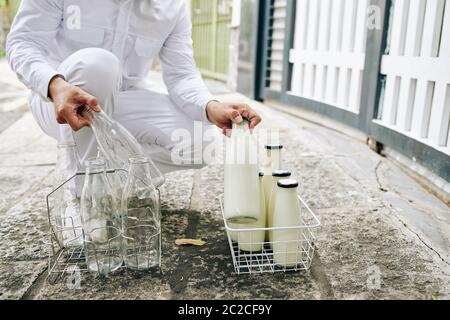 Mann Milchmann trägt perfekte weiße Outfit liefert frische Milch und nehmen leere Flaschen zurück in den frühen Morgen, kopieren Platz Stockfoto