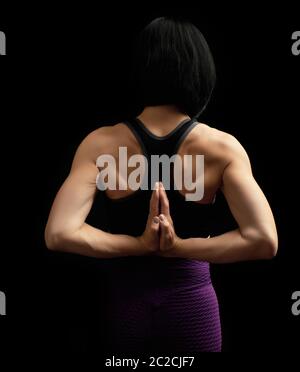 Junge Frau mit einem Sport Abbildung und Muskeln verband ihre Hände hinter dem Rücken, Hände macht eine Geste von Namaste, Low Key Stockfoto